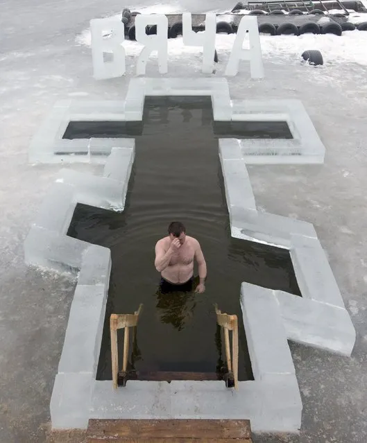 A man crosses himself as he dips into the icy waters of a lake as part of celebrations for Epiphany, near the village of Pilnitsa, northeast of Minsk January 19, 2015. (Photo by Vasily Fedosenko/Reuters)