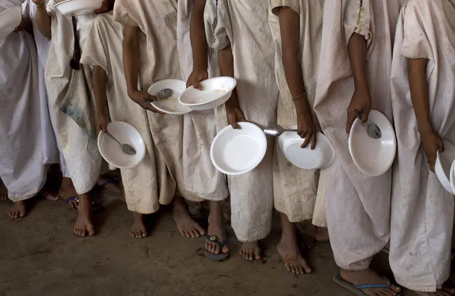 In this November 19, 2015 photo, students with bowls and spoons line up for a free breakfast provided by a government food program targeted at public schools, in Potsoteni, an Ashaninka indigenous community in Peru's Junin region. One of the government programs aims at school children, bringing food to a little more than 3,000 students in communities along the Ene River basin. (Photo by Rodrigo Abd/AP Photo)