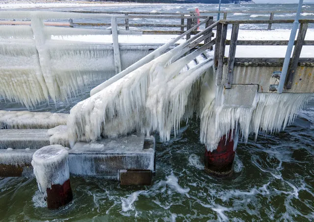 A thick layer of ice has formed at temperatures of minus five degrees on the pier on the island of Ruegen, Germany, Thursday, February 11, 2021. The bridge is closed to pedestrians because of the icing. (Photo by Jens Buettner/dpa via AP Photo)