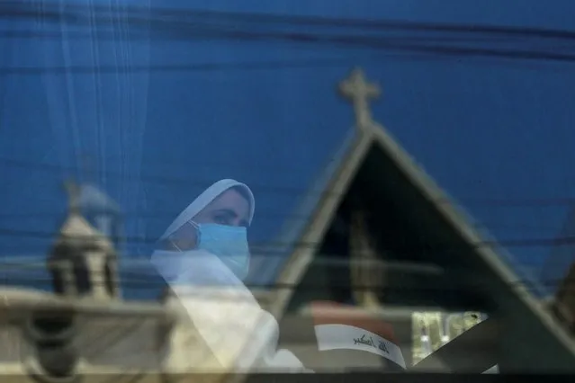 A nun in a bus holds an Iraqi flag as she heads to the airport to wait for the arrival of Pope Francis, in Baghdad, Iraq on March 5, 2021. (Photo by Abdullah Dhiaa al-Deen/Reuters)