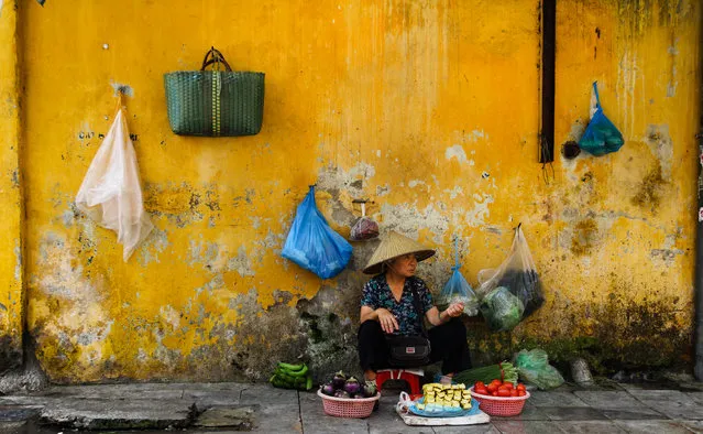 “Taken in Hanoi, Vietnam, on a street where people were selling fruit and vegetables. I was particularly drawn to this lady as she was on her own and the vibrant yellow wall made for a striking background”. (Photo by Ian Webb/The Guardian)