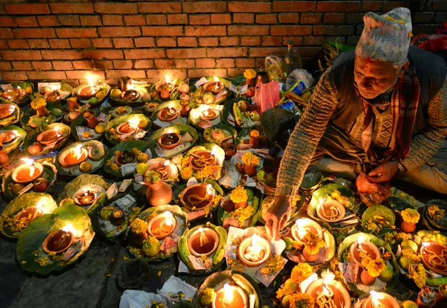 A Nepalese Hindu devotee lights oil lamp in memory of deceased family members during the Balachaturdashi festival at the Pashupatinath Temple in Kathmandu on November 27, 2016.  Devotees sow seven kinds of seeds around temple premises in the name of departed family members in observance of the festival. (Photo by Prakash Mathema/AFP Photo)