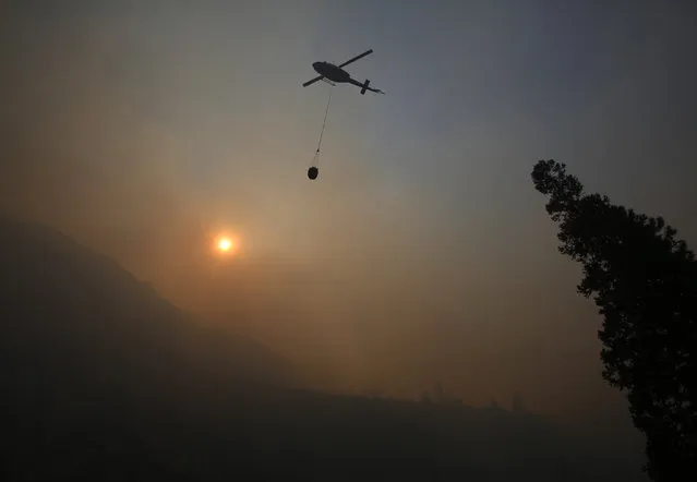 A fire helicopter takes off through smoke rising to make a drop on active fires in Yosemite National Park after the park reopened after a three week closure from smoke and fires that led to most tourists canceling their trips Tuesday, August 14, 2018 in Yosemite, Calif. (Photo by Gary Kazanjian/AP Photo)