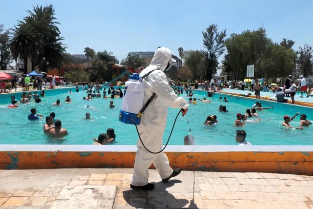 A worker at the Balneario Olímpico Pantitlán spa in Mexico City sanitizes its facilities on April 3, 2021, while visitors enjoy the Holy Week and Easter vacations during the COVID-19 health emergency and the orange epidemiological traffic light in the capital. Mexico ranks thirteenth in the world in terms of infections and third in terms of deaths due to the pandemic, more than 200,000, behind the United States and Brazil, according to Johns Hopkins University. (Photo by Gerardo Vieyra/NurPhoto/Rex Features/Shutterstock)