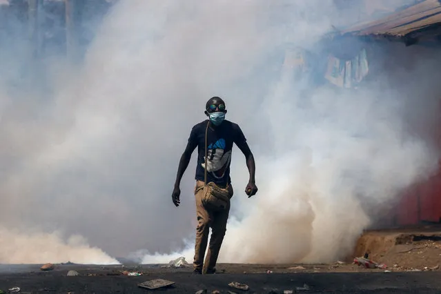 A protester walks amid smoke as supporters of Kenya's opposition leader Raila Odinga of the Azimio La Umoja (Declaration of Unity) One Kenya Alliance, participate in an anti-government protest against the imposition of tax hikes by the government in Nairobi, Kenya on July 21, 2023. (Photo by Thomas Mukoya/Reuters)