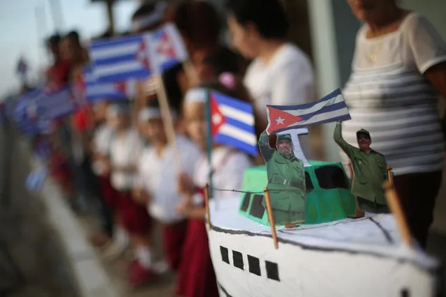 A miniature replica of the Granma yacht carries figures of Fidel and Raul Castro, as people await the arrival of the caravan carrying the ashes of Fidel Castro in Guaimaro, Cuba, December 2, 2016. (Photo by Edgard Garrido/Reuters)