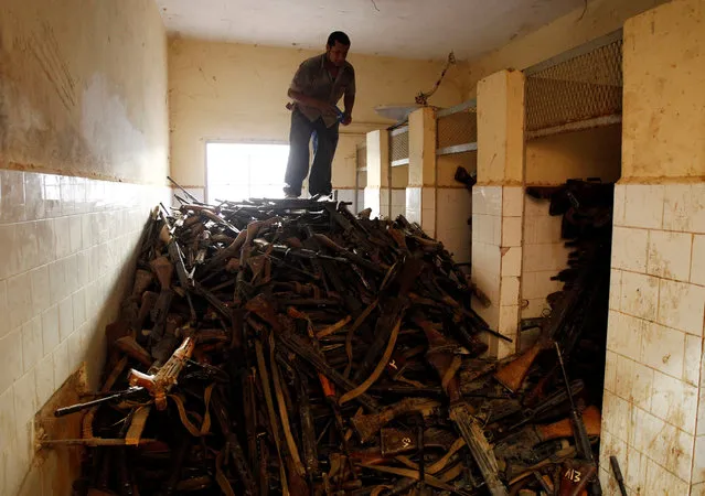 An anti-Gaddafi fighter salvages weapons from a pro-Gaddafi weapons and ammunition compound in a village near Sirte, one of Muammar Gaddafi's last remaining strongholds September 19, 2011. (Photo by Goran Tomasevic/Reuters)