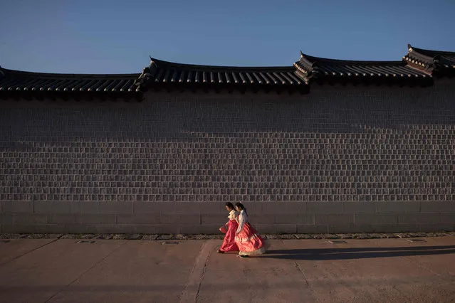 Two women wearing traditional hanbok dress walk along a wall of Gyeongbokgung palace in central Seoul on September 12, 2017. (Photo by Ed Jones/AFP Photo)