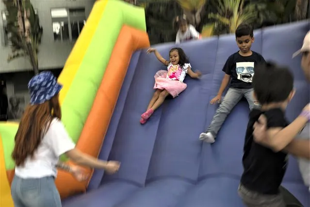 A girl, wearing a Barbie T-shirt, plays on an inflatable slide during a Children's Day celebration for pediatric patients and the children of university employees, in Caracas, Venezuela, Tuesday, July 25, 2023. (Photo by Ariana Cubillos/AP Photo)