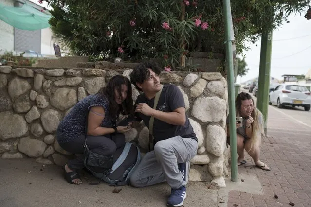Israelis take cover from the incoming rocket fire from the Gaza Strip in Ashkelon, southern Israel, Wednesday, October 11, 2023. (Photo by Leo Correa/AP Photo)