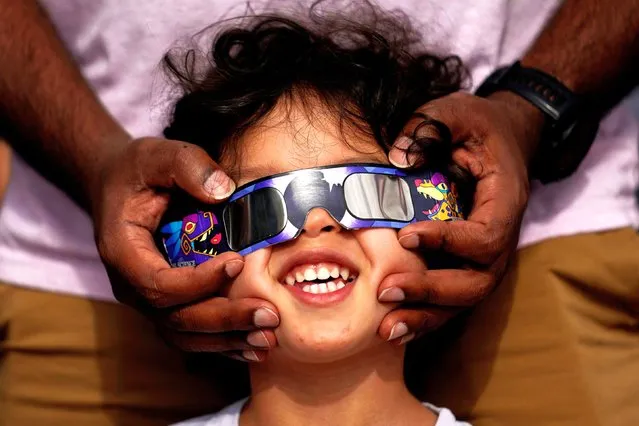 Viewers use special glasses to watch from San Antonio, as the moon moves in front of the sun during an annular solar eclipse, or ring of fire, Saturday, October 14, 2023. (Photo by Eric Gay/AP Photo)