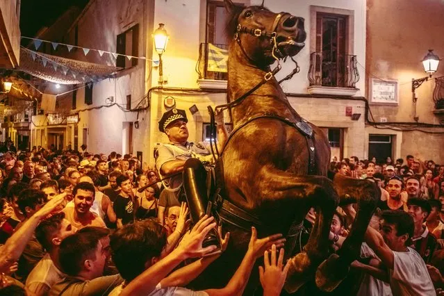 A “caixer” (horse rider) rears up on his horse surrounded by a cheering crowd during the traditional “Jaleo” at the Sant Llorenc Festival in Alaior, Spain on August 14, 2022. (Photo by Matthias Oesterle/Alamy Live News)