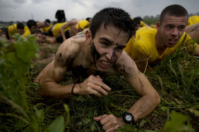 In this Friday, February 13, 2015 photo, Israeli high-school seniors crawl through grass during an exercise at a privately run training camp for military combat fitness near Yakum, central Israel. (Photo by Oded Balilty/AP Photo)