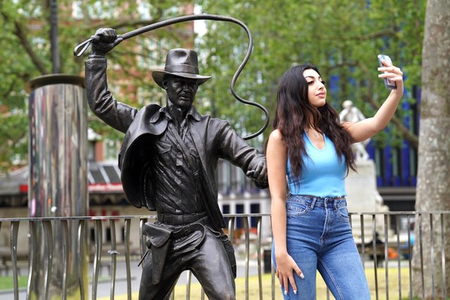 A person taking a selfie on Wednesday, June 28, 2023 with a life-sized bronze statue of the character Indiana Jones which has been unveiled as the latest addition to the Leicester Square's “Scenes in the Square” statue trail, immortalising the hero played by Harrison Ford with his whip and fedora from the 1981 film Raiders of the Lost Ark. (Photo by Stefan Rousseau/PA Images via Getty Images)