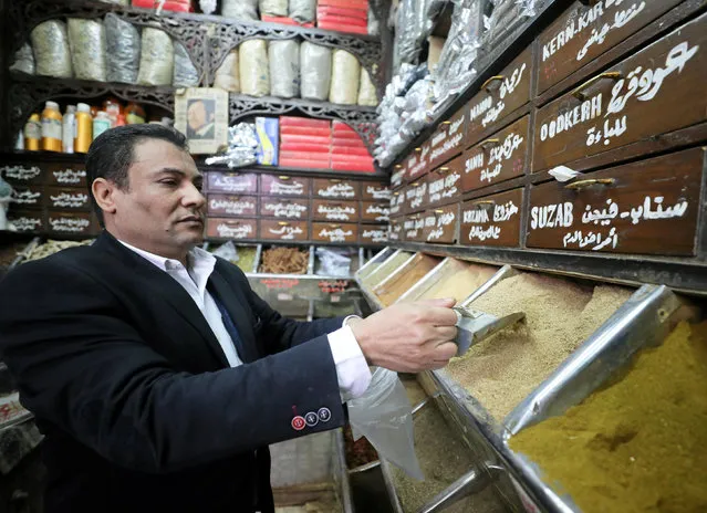 Samy Al Aatar, owner of a herbal store, takes ingredients to prepare natural herbal drug in Cairo, Egypt January 10, 2017. In an economic crisis that has led to a shortage of medicines, Egyptians are skipping trips to drug stores and instead turning to herbal remedies to treat every-day illnesses. In the Cairo working class neighborhood of Basateen, dozens line up outside a decades-old herbal spice shop with pyramid-shaped stacks of jars on display, filled with everything from honey and ginger to camel's hay. Apothecaries say there has been a roughly 70-80 percent increase in sales of their wares since a series of harsh economic reforms hit supplies of conventional medicines and increased the cost of some generic and even life-saving drugs. The government said on Thursday those price rises could reach as high as 15 percent for domestically-produced medicines and 20 percent for imports. Store owner Samy al-Attar – whose last name is Arabic for apothecary – says a knowledgeable apothecary can find substitutes for drugs treating almost all non-terminal illnesses. Just like pharmacies, the walls inside al-Attar's store are lined with drawers and containers. But rather than drugs, they hold herbs, each said to have its own unique healing property. Customers crowd outside the shop window, as staff dash around the tiny interior, choosing from a variety of textures and colors, filling clear plastic bags with orders. Customers explain their symptoms and Al-Attar produces a concoction of spices and herbs – with a more affordable price tag then at the conventional chemists. Local spices and herbs cost between 5 and 10 Egyptian pounds ($0.27-0.54) per kilogram. (Photo by Mohamed Abd El Ghany/Reuters)
