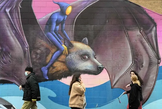 People walk past a mural by artist Hayden Dewar in Melbourne on August 16, 2021, as a coronavirus curfew from 9pm to 5am to begin later this evening was announced for Australia's second-biggest city. (Photo by William West/AFP Photo)