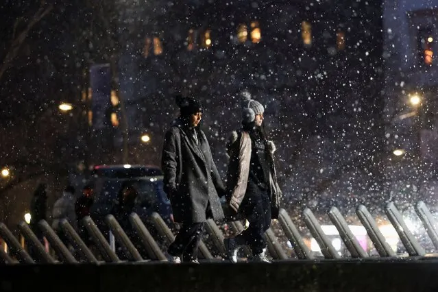 People walk as snow falls in New York City, U.S. on January 6, 2024. (Photo by Andrew Kelly/Reuters)