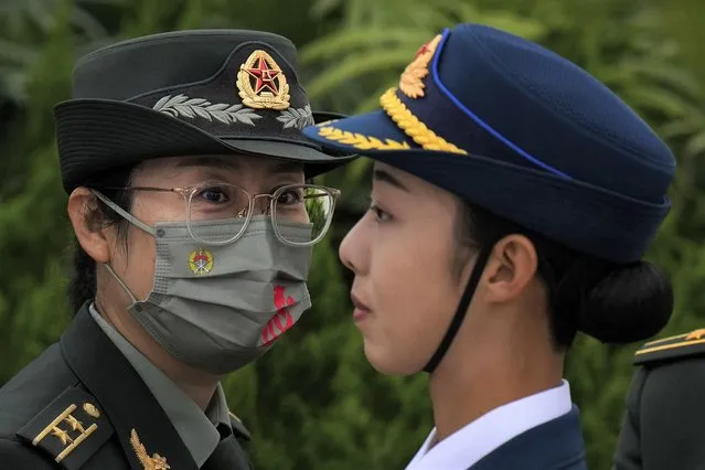 A female military officer wearing a face mask to help protect from the coronavirus looks at a female honor guard stands on Tiananmen Square during a ceremony to mark Martyr's Day in Beijing, Thursday, September 30, 2021. (Photo by Andy Wong/AP Photo)
