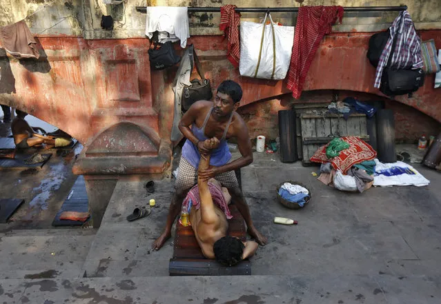 A masseur gives a massage to a customer on the banks of the river Ganges in Kolkata, India, March 3, 2016. (Photo by Rupak De Chowdhuri/Reuters)