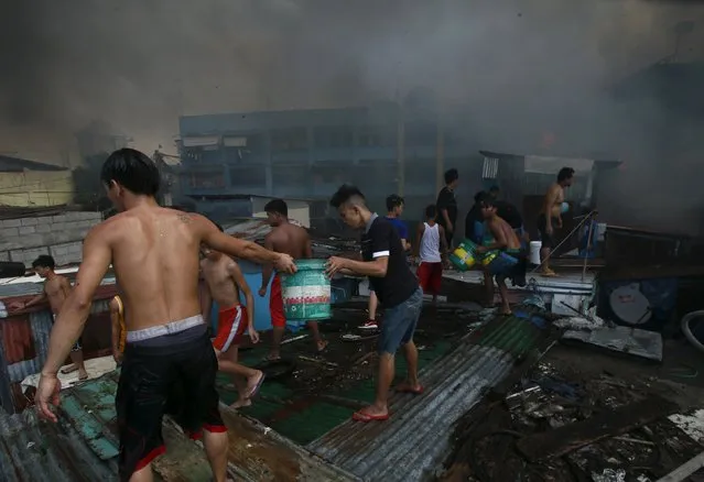 Residents use pails of water to splash on the charred houses after a fire razed through residential area in San Andres Bukid, metro Manila March 12, 2016. (Photo by Romeo Ranoco/Reuters)