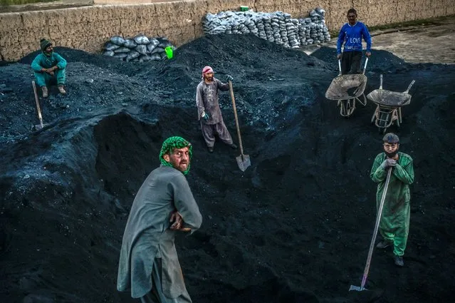 Hazara workers prepare to load coal onto a truck near the site where the Salsal Buddha statue once stood before being destroyed by the Taliban in March 2001, in Bamiyan province on October 3, 2021. (Photo by Bulent Kilic/AFP Photo)