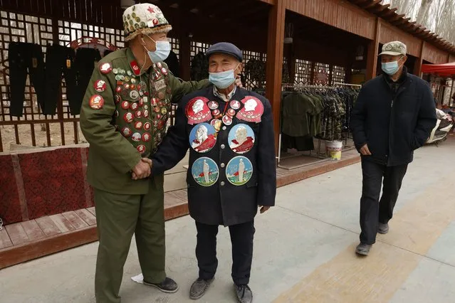 Ethnic minority veterans wearing commemorative buttons, some featuring Chairman Mao Zedong, greet each other at a flea market in Poksam county in northwestern China's Xinjiang Uyghur Autonomous Region on March 21, 2021. Four years after Beijing's brutal crackdown on largely Muslim minorities native to Xinjiang, Chinese authorities are dialing back the region's high-tech police state and stepping up tourism. But even as a sense of normality returns, fear remains, hidden but pervasive. (Photo by Ng Han Guan/AP Photo)