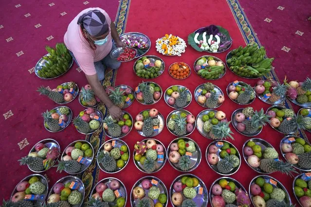 A devotee prepares fruits and flower offerings to Hindu Goddess Lakshmi during the Hindu festival of lights, Diwali at Vishnu temple in Bangkok, Thailand, Thursday, November 4, 2021. Millions of people across Asia are celebrating the Hindu festival of Diwali, which symbolizes new beginnings and the triumph of good over evil and light over darkness. (Photo by Sakchai Lalit/AP Photo)