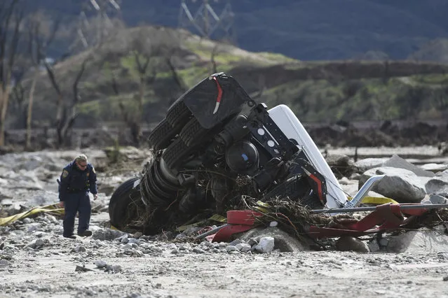 An official looks over the scene, Saturday, February 18, 2017,  where a tractor trailer and a San Bernardino County Fire Department fire engine fell Friday from southbound Interstate 15 where part of the freeway collasped due to heavy rain in the Cajon Pass, Calif.   A huge Pacific storm that parked itself over Southern California and unloaded, ravaging roads, opening sinkholes  eased off Saturday but it was only a temporary reprieve as new storms took aim farther north. (Photo by David Pardo/The Daily Press via AP Photo)