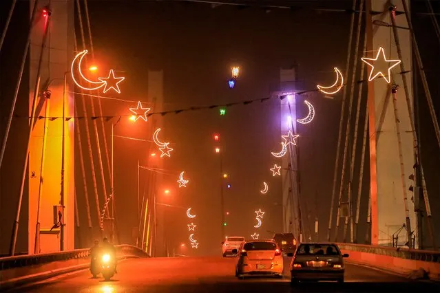 Vehicles move beneath decorations set up for the Muslim holy month of Ramadan across the Hadarat (Civilisations) bridge amidst reduced visibility conditions due to a dust storm in Nasiriyah, the capital of Iraq's southern Dhi Qar province, on March 18, 2024. (Photo by Asaad Niazi/AFP Photo)