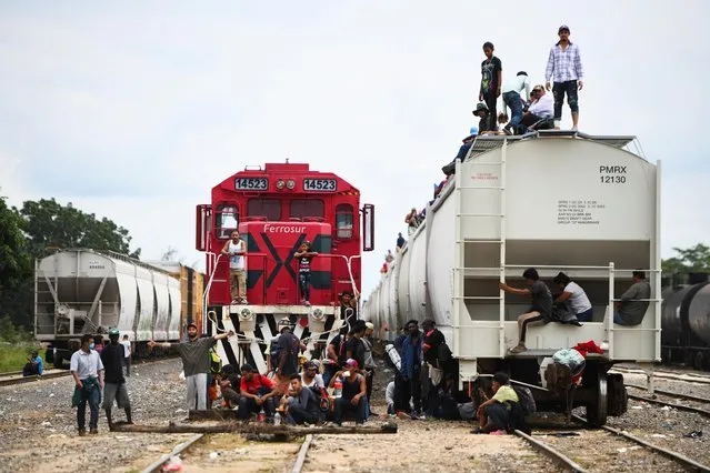 Migrants from Central America sit on freight cars and railroads as they wait for the departure of a freight train to continue their journey towards Mexico City, in Tierra Blanca, Veracruz, Mexico on December 2, 2021. (Photo by Yahir Ceballos/Reuters)