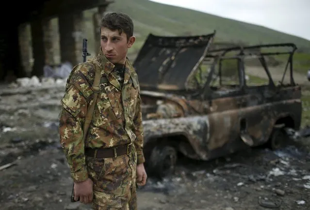 A serviceman of the self-defense army of Nagorno-Karabakh stands next to a destroyed military car in the village of Talish April 6, 2016. (Photo by Reuters/Staff)