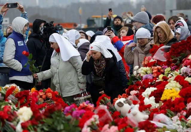 People lay flowers at a makeshift memorial to the victims of a shooting attack set up outside the Crocus City Hall concert venue in the Moscow Region, Russia, on March 24, 2024. (Photo by Maxim Shemetov/Reuters)