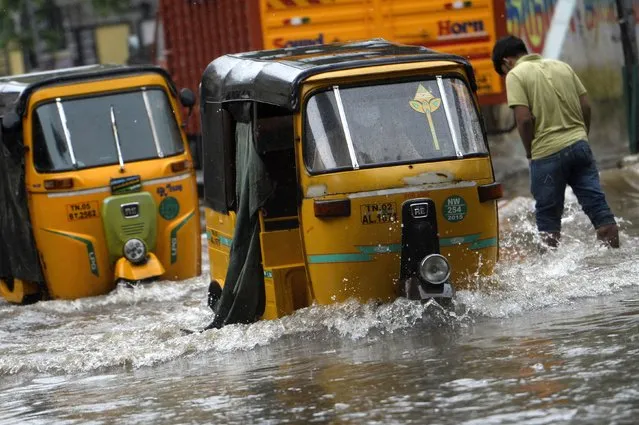 Auto-rickshaws make their way along a waterlogged street after a heavy rainfall in Chennai on December 31, 2021. (Photo by Arun Sankar/AFP Photo)