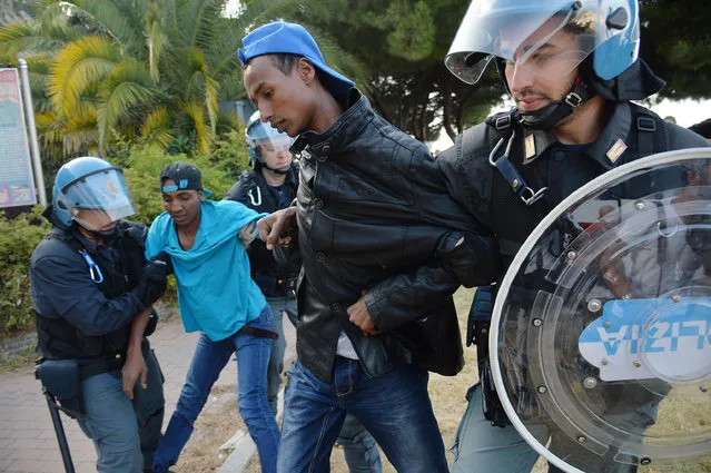 Italian police officers drag away migrants in Ventimiglia, at the Italian-French border Tuesday, June 16, 2015. Police at Italy's Mediterranean border with France have forcibly removed some of the African migrants who have been camping out for days in hopes of continuing their journeys farther north. The migrants, mostly from Sudan and Eritrea, have been camped out for five days after French border police refused to let them cross. (Luca Zennaro/ANSA via AP)