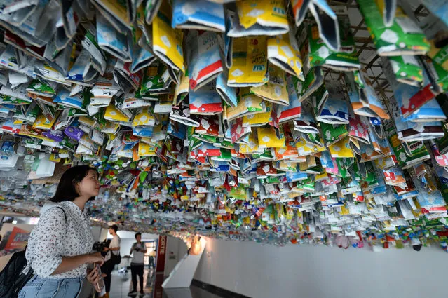 Visitors view a hanging art installation by a group of artists made from scraps of plastics, cans and containers at an exhibition “Reduce the Litter” at the French Cultural Centre in Hanoi on July 15, 2019. The exhibition takes on the perspective on production and consumption, portraying pollution from domestic waste causing harmful impact on the environment and peole's health. (Photo by Nhac Nguyen/AFP Photo)