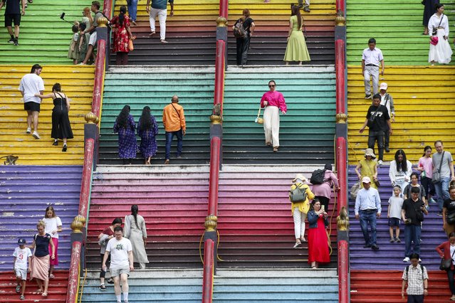 Hindu devotees and visitors walk up the colorful 272 steps to the Batu Caves Temple outside Kuala Lumpur in Gombak, Malaysia, 21 February 2024. An escalator will be built at Batu Caves this year as an alternative to the 272 steps to reach the Sri Subramaniar cave temple, which is more accessible to the disabled and elderly visitors. (Photo by Fazry Ismail/EPA)