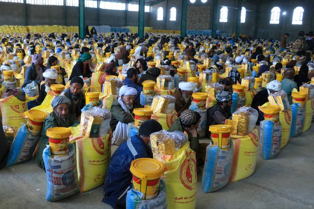 Afghan men receive food from a local charity during the Islamic holy fasting month of Ramadan in Inj?l on March 18, 2024. (Photo by Mohsen Karimi/AFP Photo)