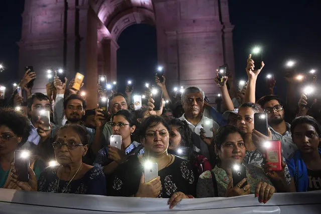 Indian social activists uses their mobile light as they take part in a solidarity rally in front of India Gate monument for the Unnao rape victim in New Delhi on July 29, 2019. An Indian teenager who accused a senior politician of rape is fighting for her life after being critically injured in a crash on July 28, 2019 that killed two relatives, raising suspicions of foul play. (Photo by Sajjad Hussain/AFP Photo)