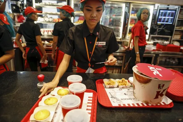 Staff prepare to sell meals at a KFC branch during its opening day in Yangon June 30, 2015. The first KFC branch in Myanmar opened on Tuesday, reported local media. (Photo by Soe Zeya Tun/Reuters)