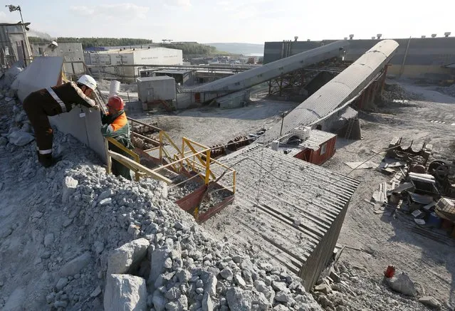 Employees speak near the crusher of a procession plant (back) of the Olimpiada gold operation, owned by Polyus Gold International company, in Krasnoyarsk region, Eastern Siberia, Russia, June 30, 2015. (Photo by Ilya Naymushin/Reuters)