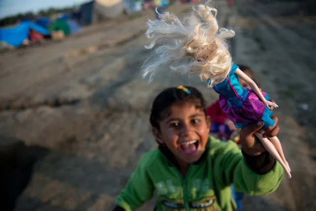 A girl plays with a doll at a makeshift camp for migrants and refugees near the village of Idomeni not far from the Greek-Macedonian border on April 30, 2016. Some 54,000 people, many of them fleeing the war in Syria, have been stranded on Greek territory since the closure of the migrant route through the Balkans in February. (Photo by Tobias Schwarz/AFP Photo)
