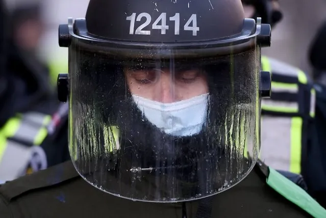 A Quebec Provincial Police officer's visor drips with condensation as police take action to put an end to a protest, which started in opposition to mandatory COVID-19 vaccine mandates and grew into a broader anti-government demonstration and occupation, Friday, February 18, 2022, in Ottawa. (Photo by Justin Tang/The Canadian Press via AP Photo)