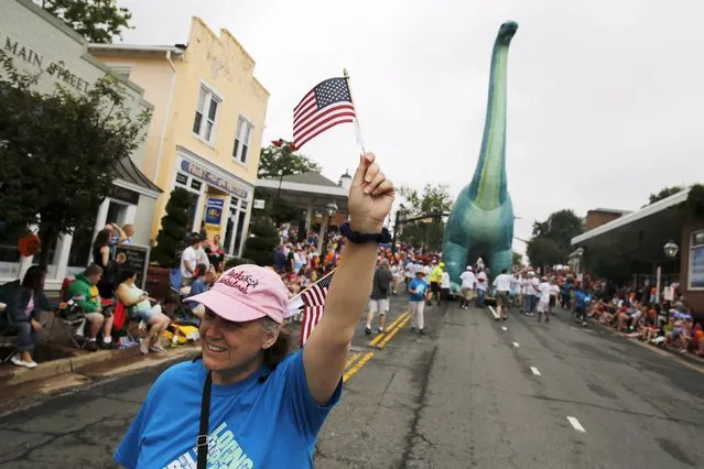 A team from Woody's Ice Cream shop wrangle a large inflatable dinosaur down the street during the Independence Day Parade in Fairfax, Virginia July 4, 2015. (Photo by Jonathan Ernst/Reuters)