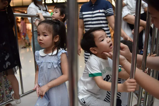 This photo taken on July 14, 2019 shows child models Yumi (L) and Yuki Xiao (R) preparing to take the stage at a child model contest in Beijing. Manicured children strut down the catwalk at a Beijing fashion show, one of thousands of events driving huge demand for child models in China that insiders warn leaves minors vulnerable to physical abuse, 12-hour-days and unrelenting pressure from pushy parents. (Photo by Greg Baker/AFP Photo)