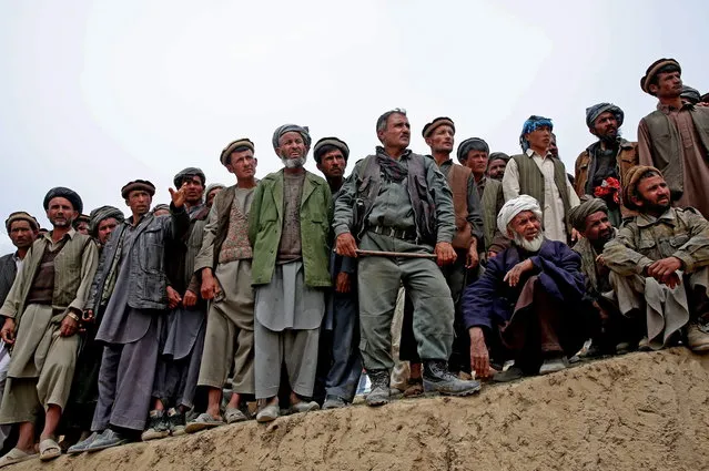 In this Sunday, May 4, 2014 photo, Survivors line up to receive donations near the site of Friday's landslide that buried Abi-Barik village in Badakhshan province, northeastern Afghanistan. The landslide Friday killed hundreds of people – still no one has an exact number – and destroyed 300 homes and displaced hundreds more families. (Photo by Massoud Hossaini/AP Photo)