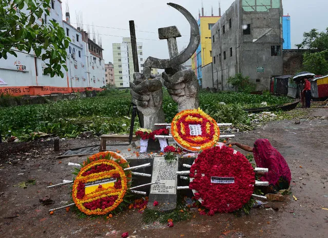 A Bangaldeshi relative of a victim kiled in the Rana Plaza building collapse sit next to a monument as she marks the fourth anniversary of the disaster at the site where the building once stood in Savar, on the outskirts of Dhaka, on April 24, 2017. Thousands of Bangladeshi garment workers staged a tearful demonstration April 24 to mark the anniversary of a factory disaster that killed 1,138 people, demanding justice for the victims and better pay. (Photo by AFP Photo/Stringer)