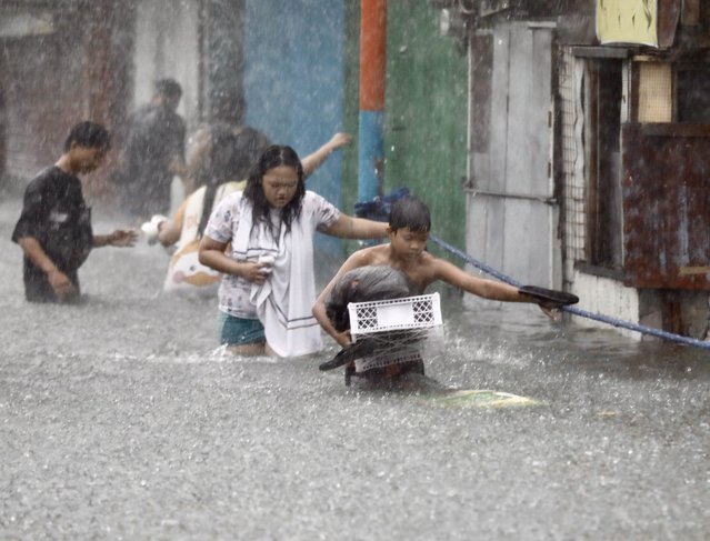 Residents carrying belongings wade on rising floodwaters in Marikina city, Metro Manila, Philippines, 24 July 2024. Interior and Local Government Secretary Benhur Abalos Junior recommended on 24 July the declaration of a state of calamity in Metro Manila as thousands of residents fleed their homes due to the massive flooding brought about by the Southwest Monsoon that is being enhanced by Typhoon Gaemi. (Photo by Francis R. Malasig/EPA/EFE)