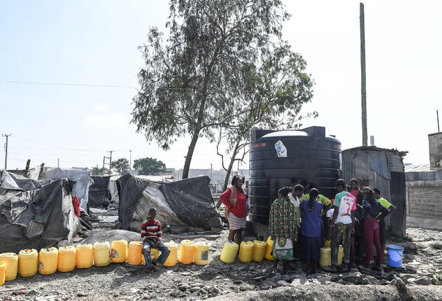 Women with jerricans queue for water next to their makeshift camp, in the Mukuru Kwa Njenga informal settlements, on March 10, 2022 after their houses were demolished on November 2021 to pave way for construction of the Nairobi Expressway within the Industrial Area. (Photo by Simon Maina/AFP Photo)