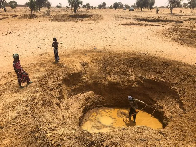 A man digs a pit to obtain water, in a dry river bed, near the village of Tata Bathily in Matam, Senegal on March 30, 2022. (Photo by Edward McAllister/Reuters)