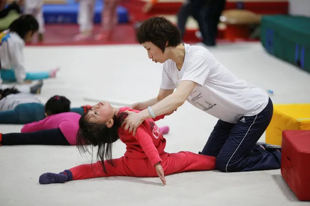 A coach helps a girl during gymnastics lessons at the Shanghai Yangpu Youth Amateur Athletic School in Shanghai, China, March 23, 2016. (Photo by Aly Song/Reuters)